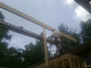Carpenter setting a ridge beam over a new addition frame — Ice Dam Removal by Roofing Brothers in Harbor Springs