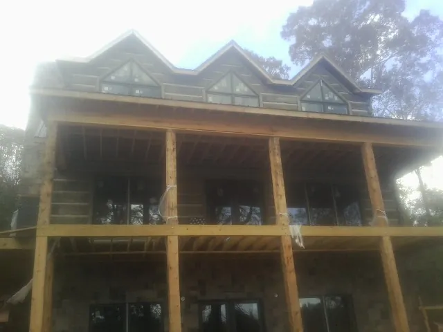 Dormers and porch framing on a large log home under construction — Roof Coating work by our crew in Harbor Springs