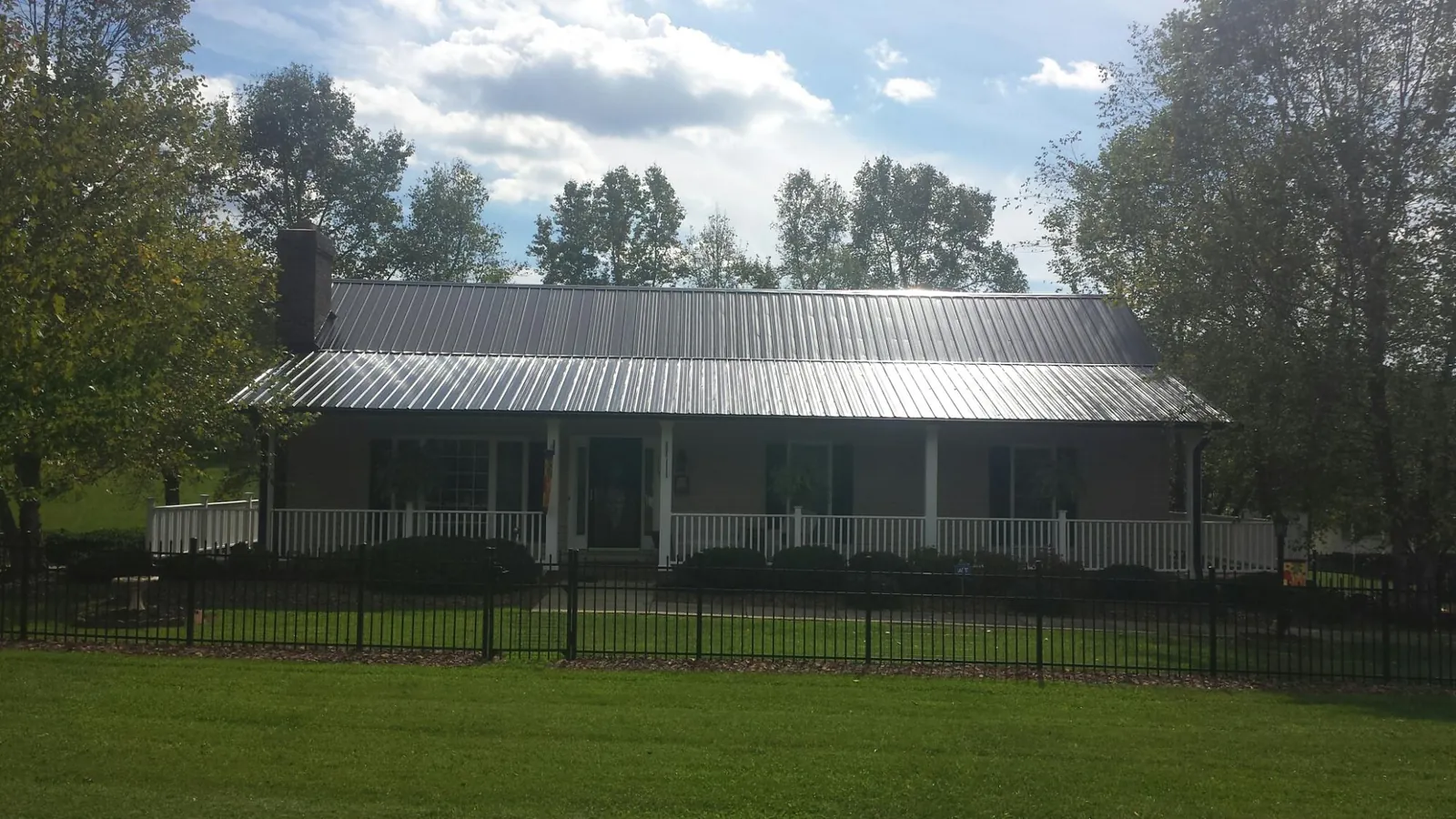 Gray metal roof on a brick ranch with a full width front porch — Gutter Guard Installation work by our crew in Harbor Springs